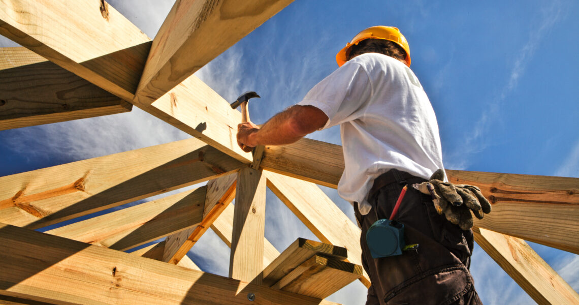 Couvreur et charpentier travaillant sur la structure du toit sur un chantier de construction.