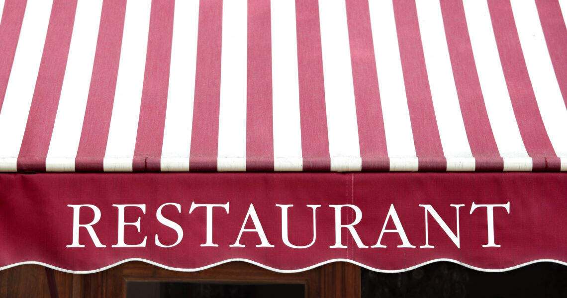 Auvent de restaurant à rayures vives à Paris. Mise au point sur le mot Restaurant.